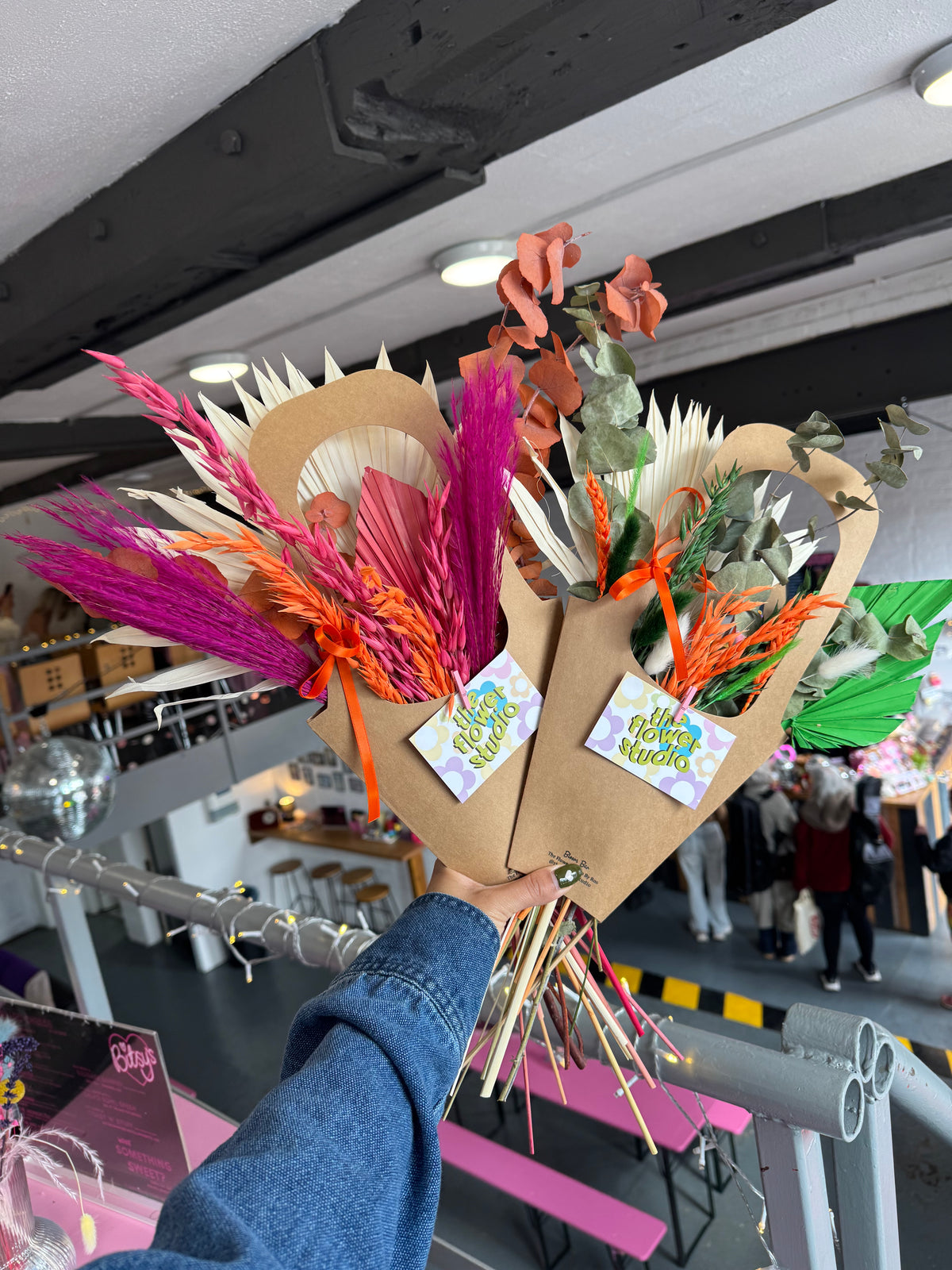 Decorative headpiece with feathers and leaves held by a person in an indoor setting.