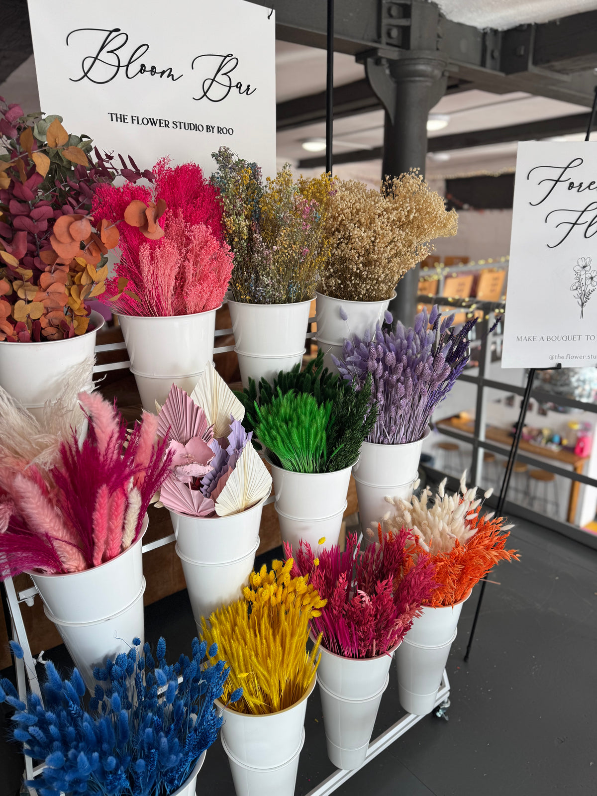 Colorful floral arrangements in white pots displayed in a store setting.