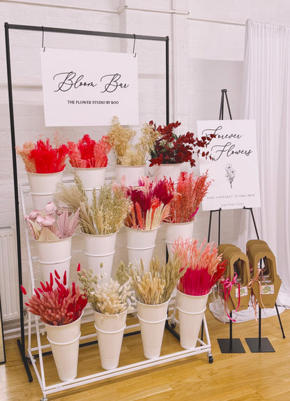 Floral arrangement display with 'Bloom Box' branding in a studio setting.