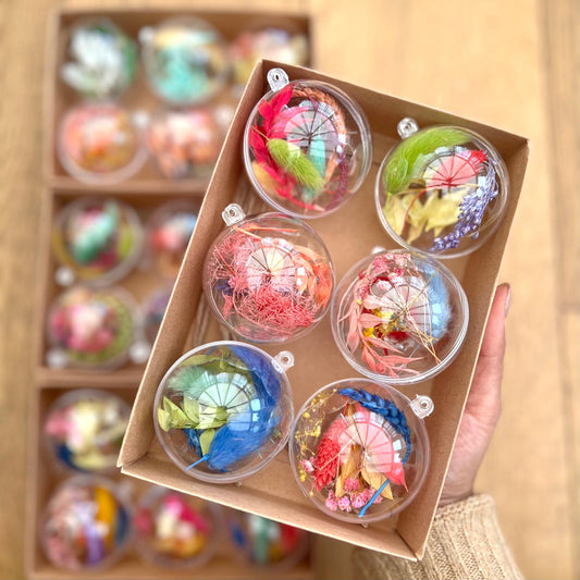 Decorative items in clear plastic spheres with floral designs, held in a cardboard box.