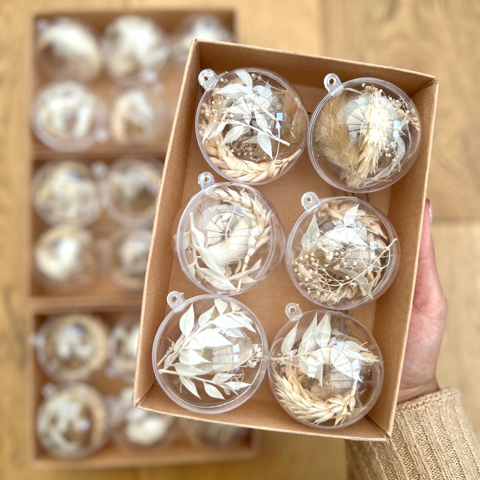 Clear spherical Christmas baubles with floral designs in a cardboard box.