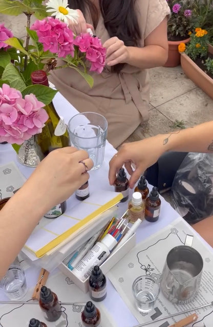 Two people working with flowers and bottles on a table outdoors.
