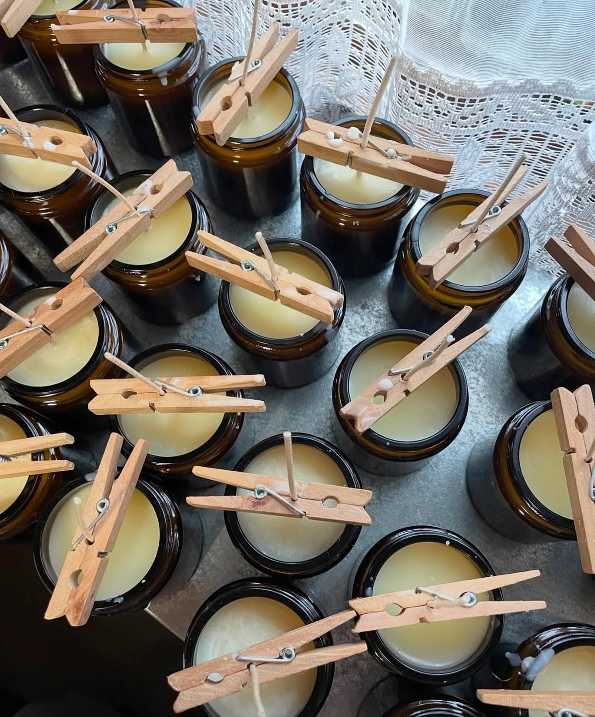 Jars of candles with wooden clothespins on a textured surface