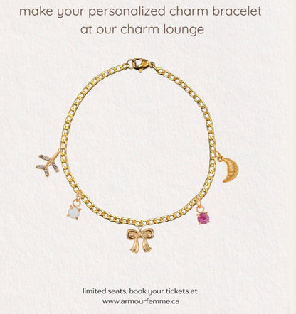 Gold charm bracelet with various charms on a light gray background