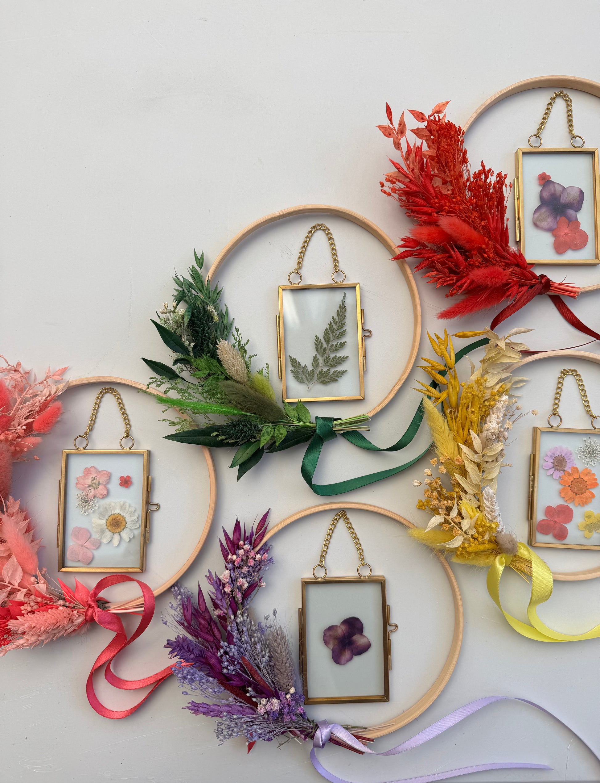 Decorative frames with dried flowers and ribbons on a light gray background