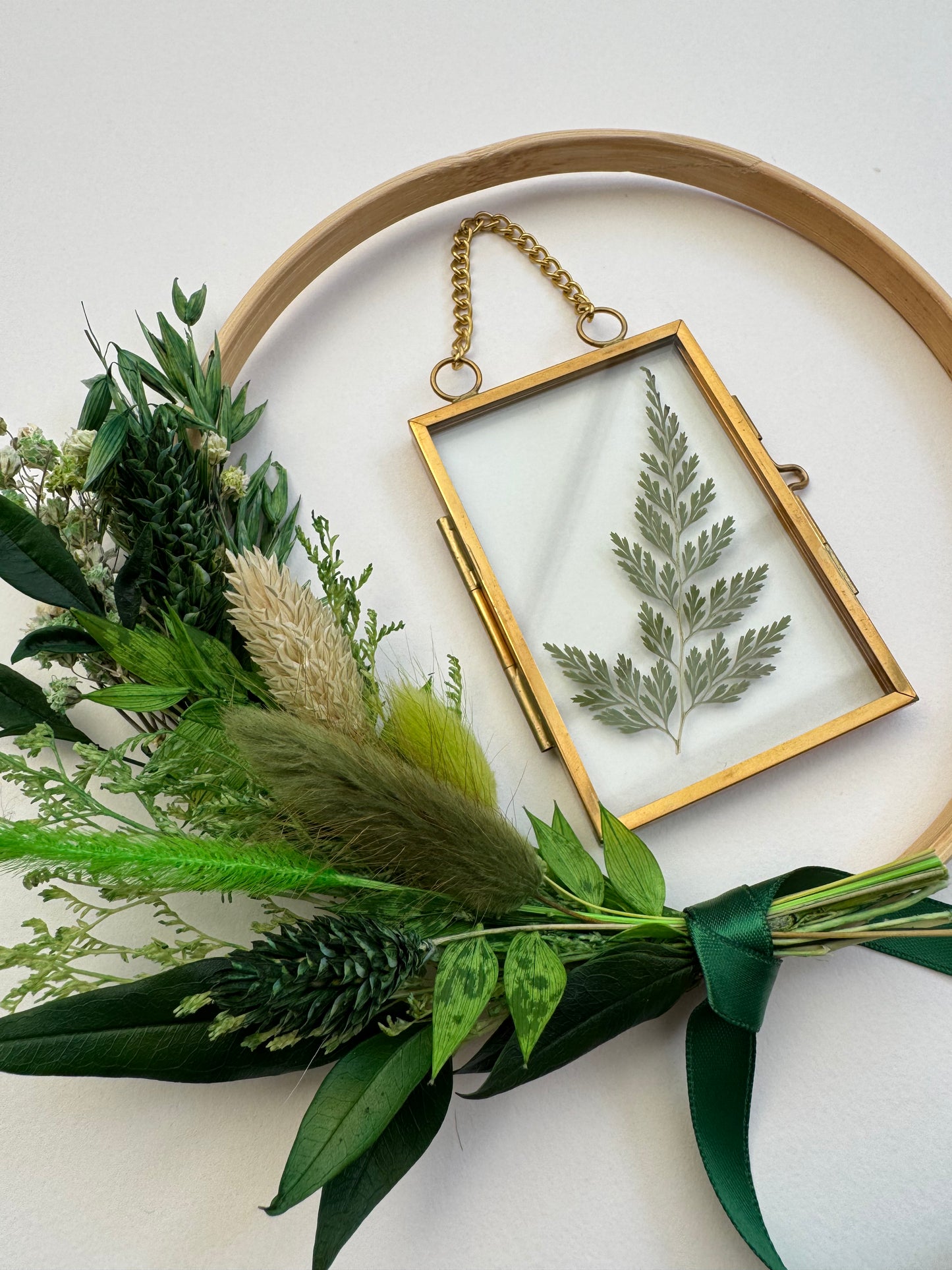 Decorative hoop with pressed fern and greenery on a white background