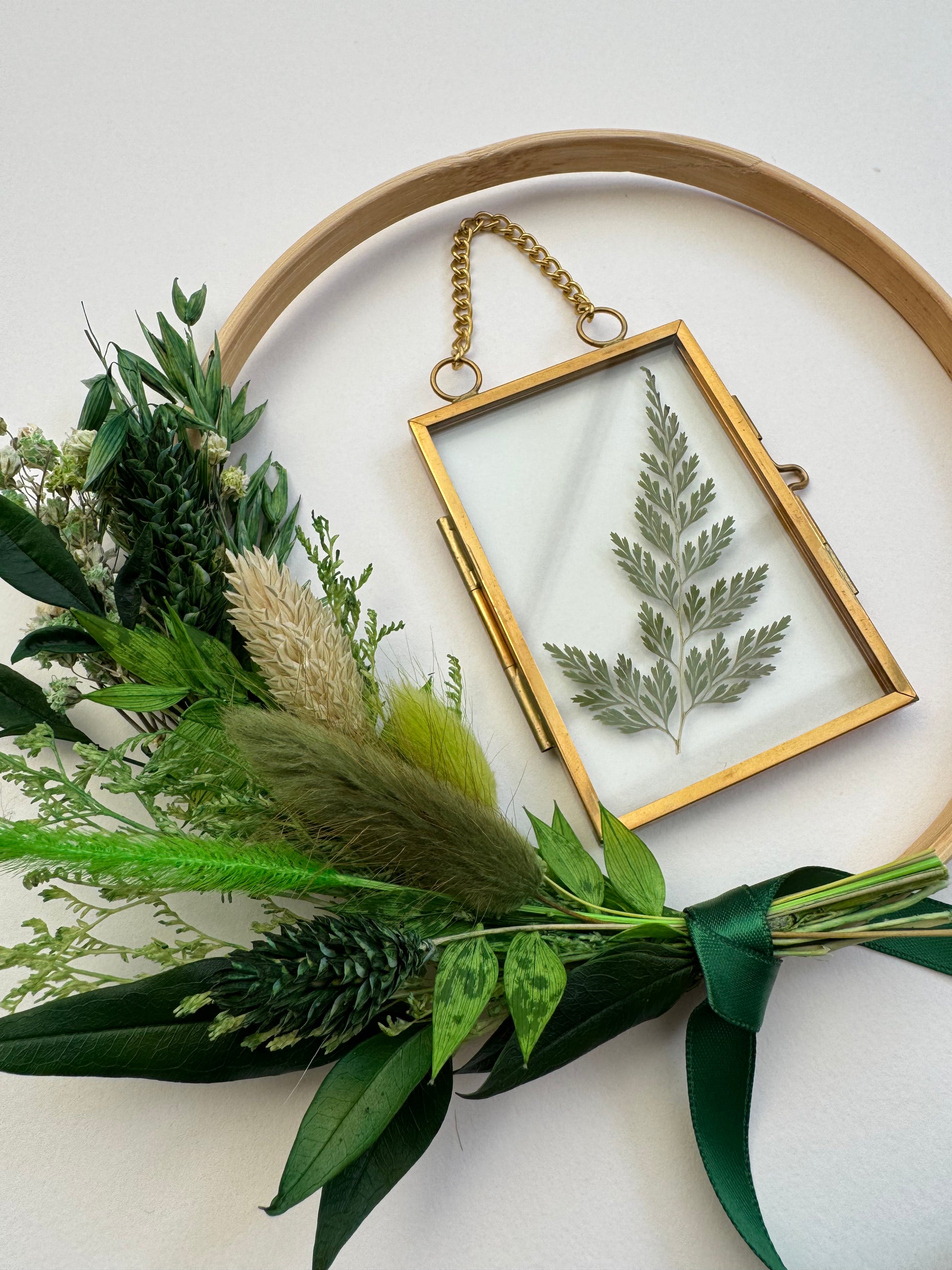 Decorative hoop with pressed fern and greenery on a white background