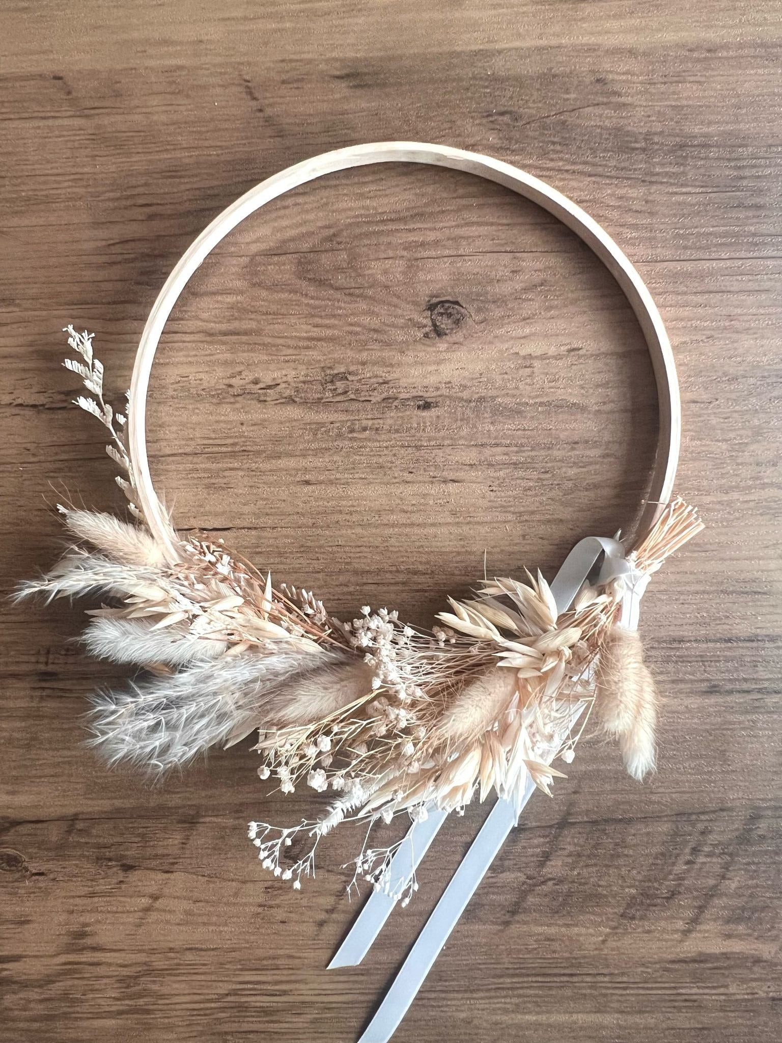 Rustic boho wreath made with soft dried flowers and natural textures, displayed against a rustic wooden table