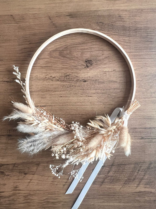 Rustic boho wreath made with soft dried flowers and natural textures, displayed against a rustic wooden table