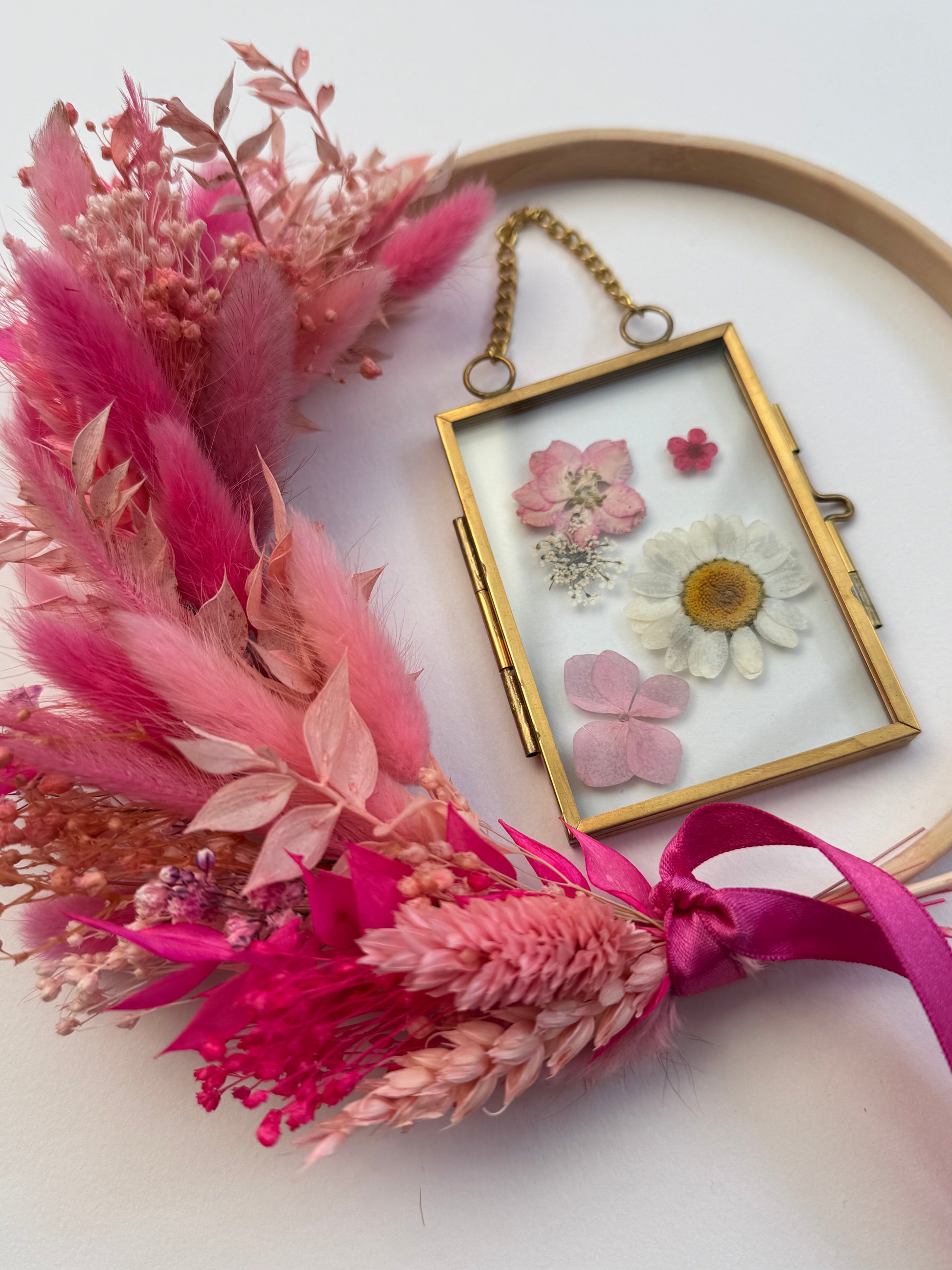 Decorative headband with pink flowers and a small framed floral piece on a white background