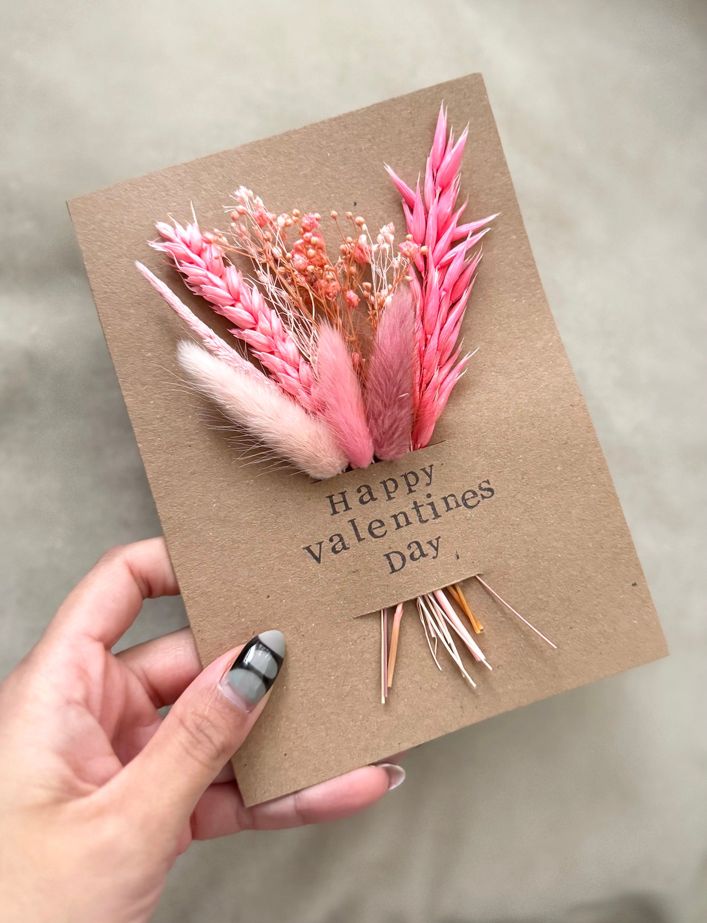 Card with pink flowers and 'Happy Valentine's Day' text held by a hand.
