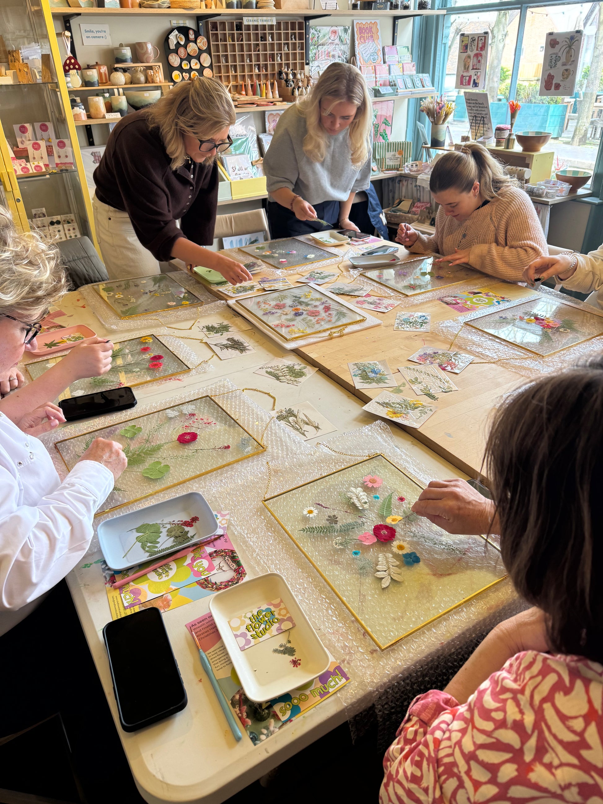 Pressed flower frame workshop in action. A group of women focused working on their floral creations 