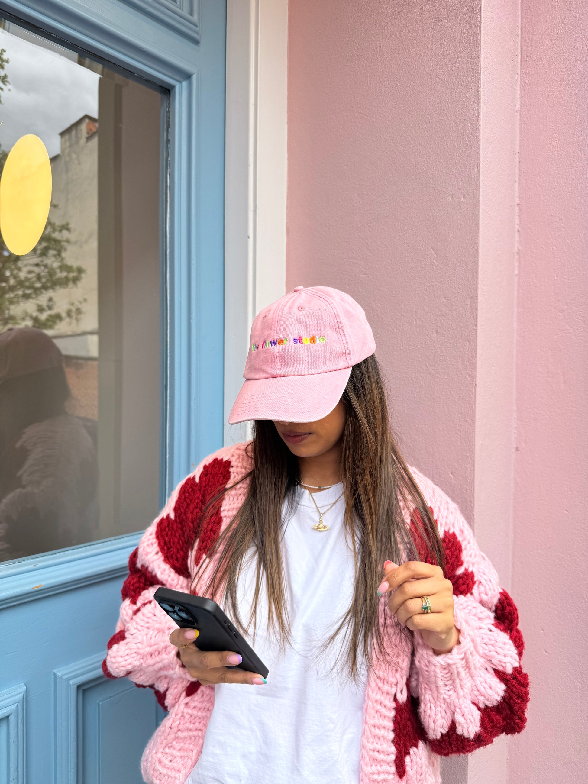 Person wearing a pink knit hat and scarf, leaning out of a window.